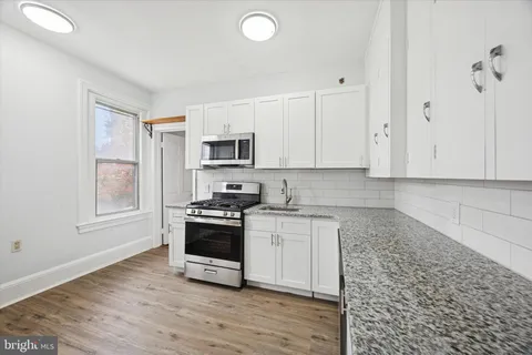 a kitchen with granite countertop a stove a sink and a microwave