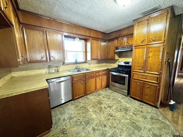 a kitchen with stainless steel appliances granite countertop a stove a sink and a refrigerator