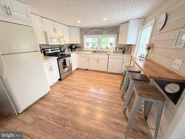 a kitchen with stainless steel appliances a sink a stove a refrigerator cabinets and a window