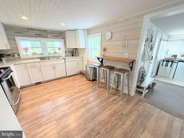 a kitchen with a sink wooden floor and white appliances