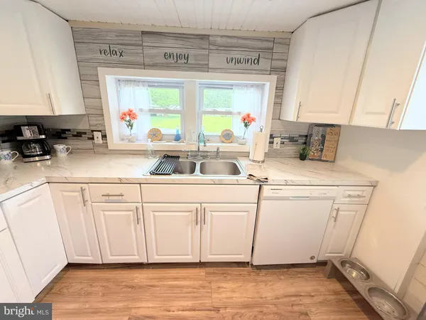 a kitchen with stainless steel appliances white cabinets a sink and a large window