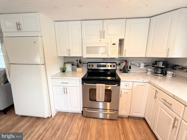 a kitchen with a refrigerator a stove a sink and white cabinets with wooden floor