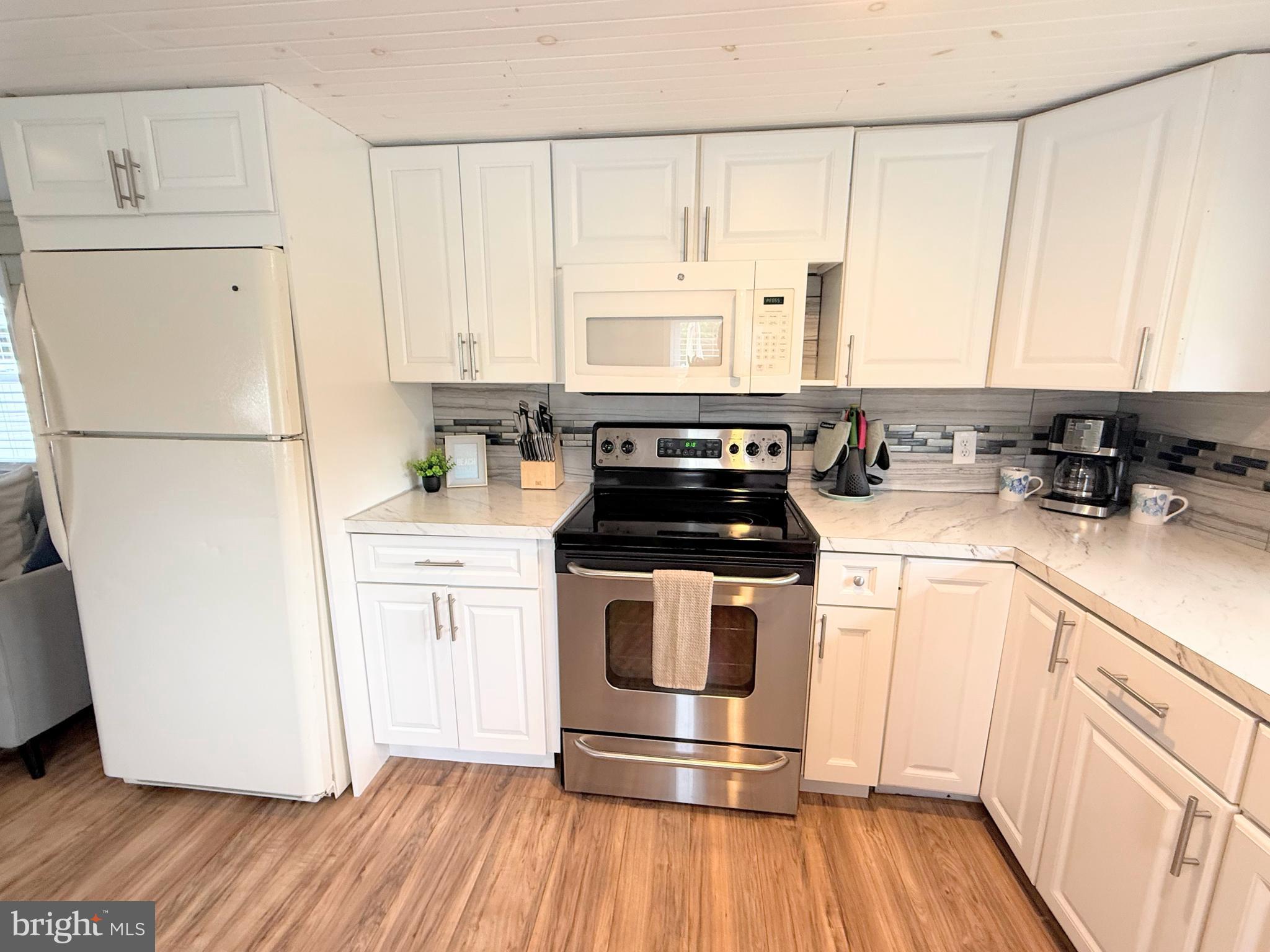 34635 Deck Street, Unit E323 Long Neck, DE 19966 - Photo 19 of 44 a kitchen with a refrigerator a stove a sink and white cabinets with wooden floor