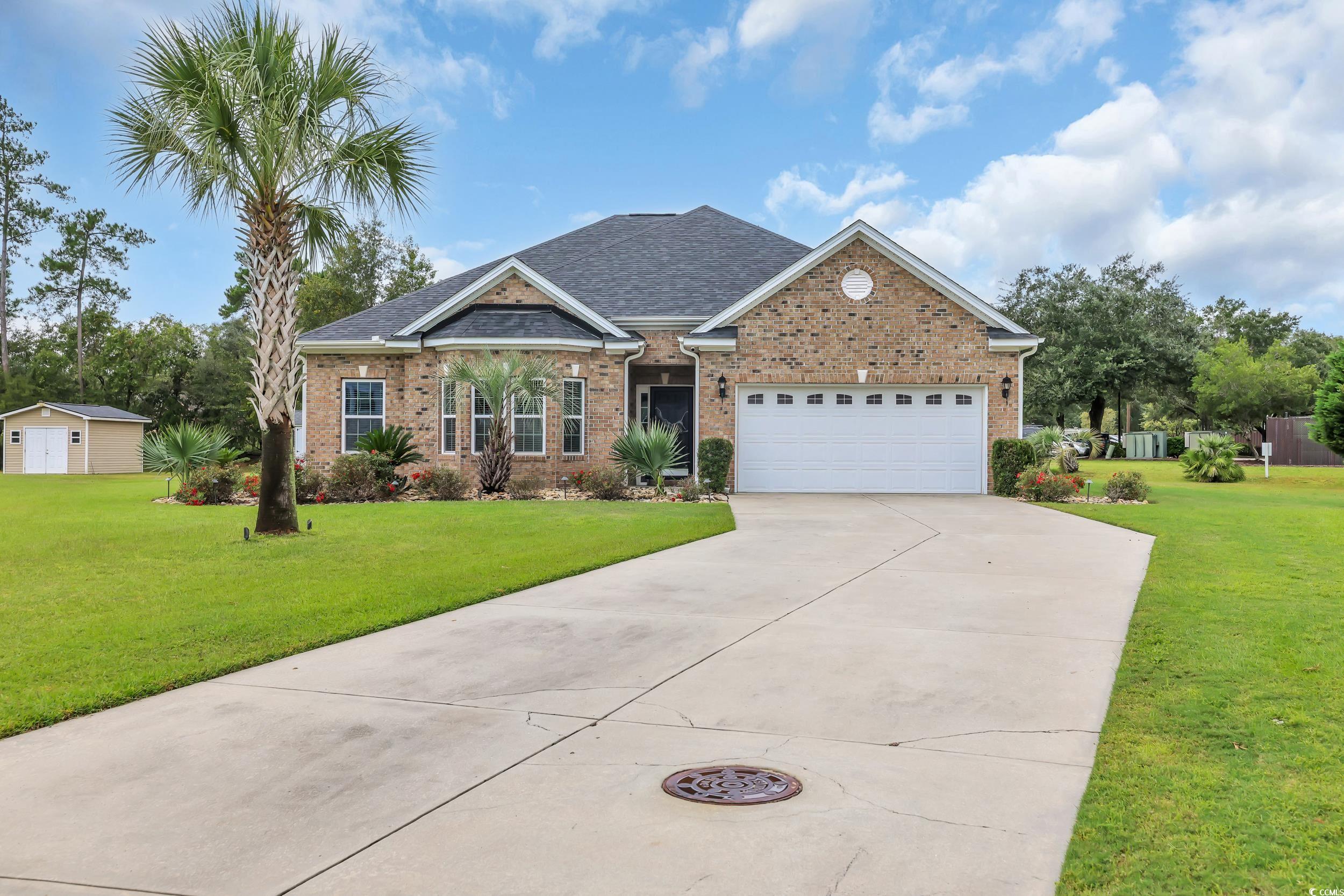 Single story home with a front yard, a shingled roof, brick siding, and concrete driveway