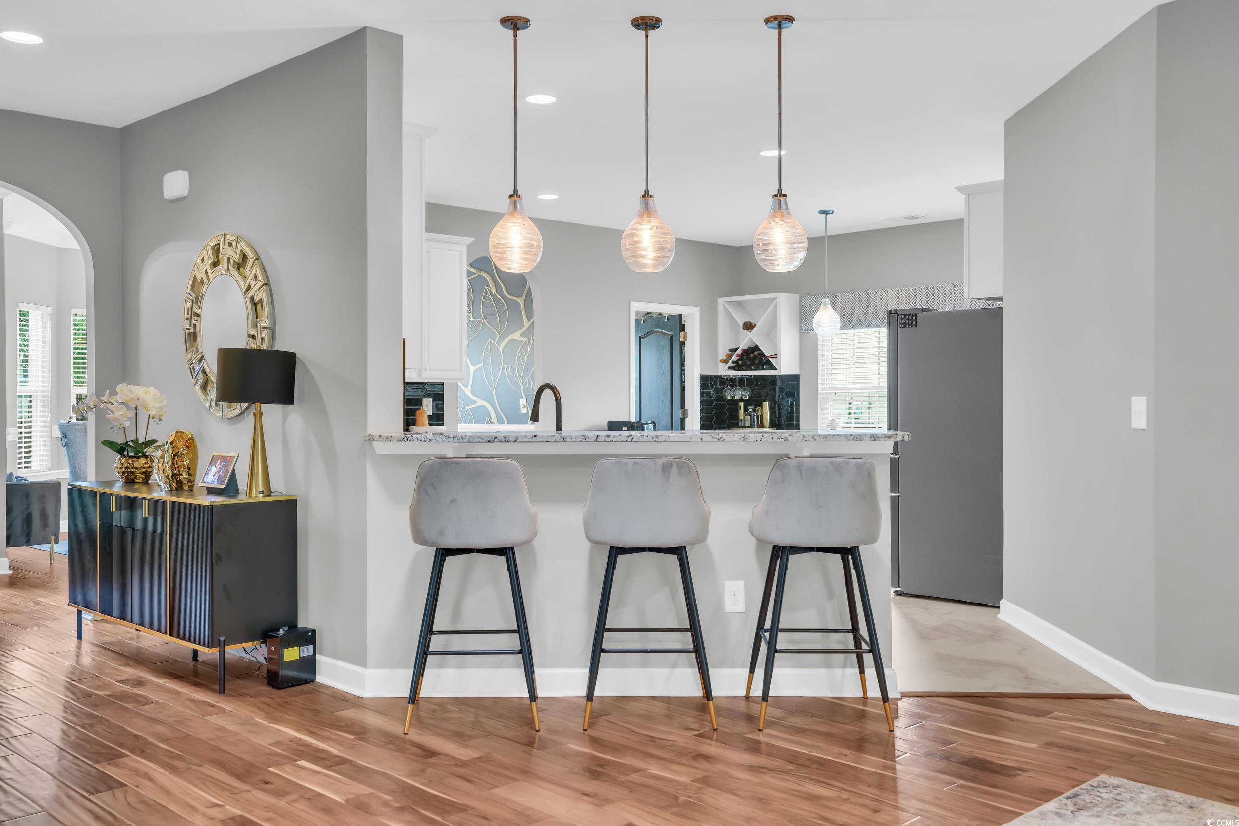 1705 Brookshade Court Conway, SC 29526 - Photo 11 of 40 Kitchen with a breakfast bar, white cabinets, freestanding refrigerator, light wood-type flooring, and decorative light fixtures