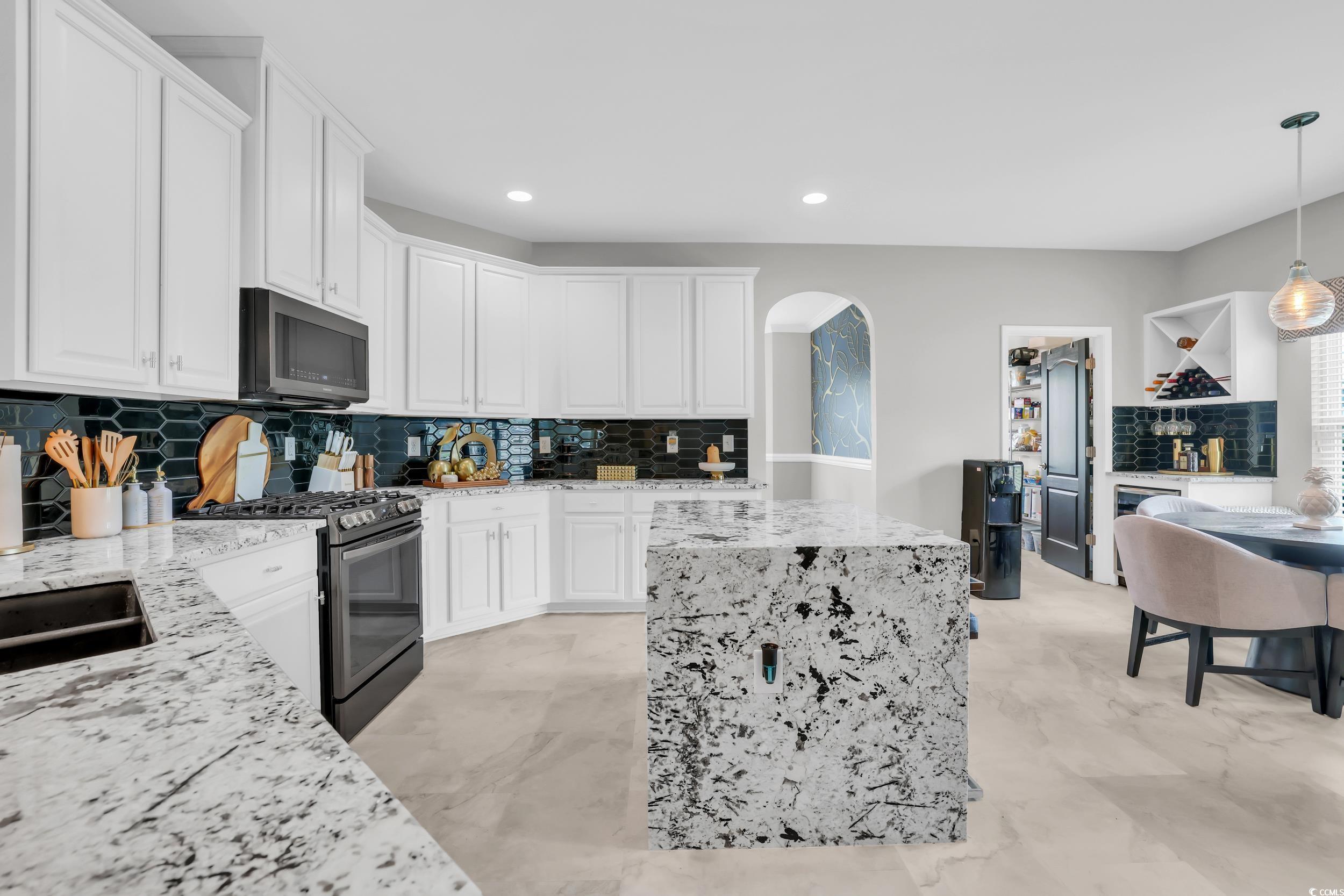 1705 Brookshade Court Conway, SC 29526 - Photo 9 of 40 Kitchen with backsplash, arched walkways, gas stove, white cabinetry, and light stone countertops