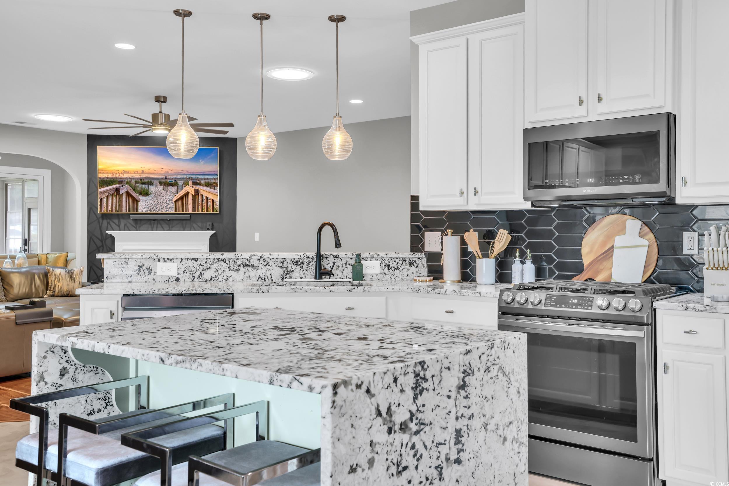 1705 Brookshade Court Conway, SC 29526 - Photo 10 of 40 Kitchen with a peninsula, light stone countertops, stainless steel appliances, backsplash, and a kitchen breakfast bar