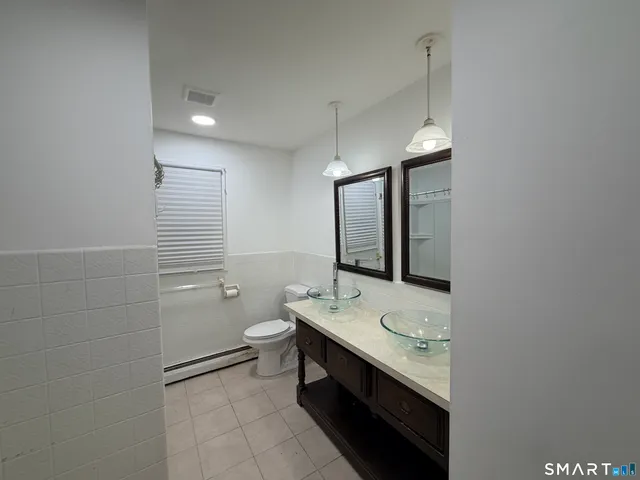 a bathroom with a double vanity sink toilet and mirror