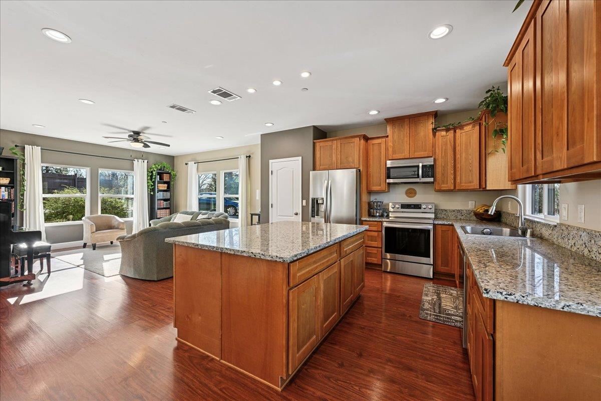 21895 One Fine Place Colfax, CA 95713 - Photo 21 of 82 a kitchen with stainless steel appliances granite countertop a stove top oven a sink dishwasher a dining table and chairs with wooden floor