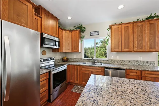 a living room with stainless steel appliances granite countertop furniture wooden floor and a rug