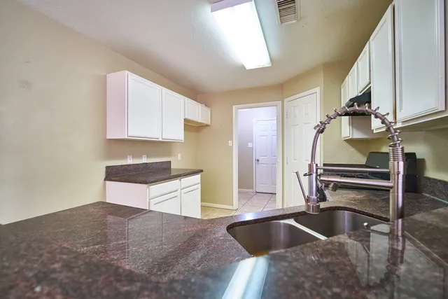 a kitchen with granite countertop a stove and white cabinets