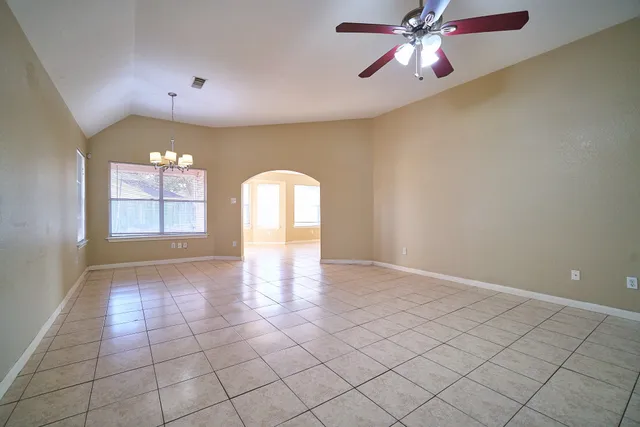 a view of empty room with window and chandelier fan