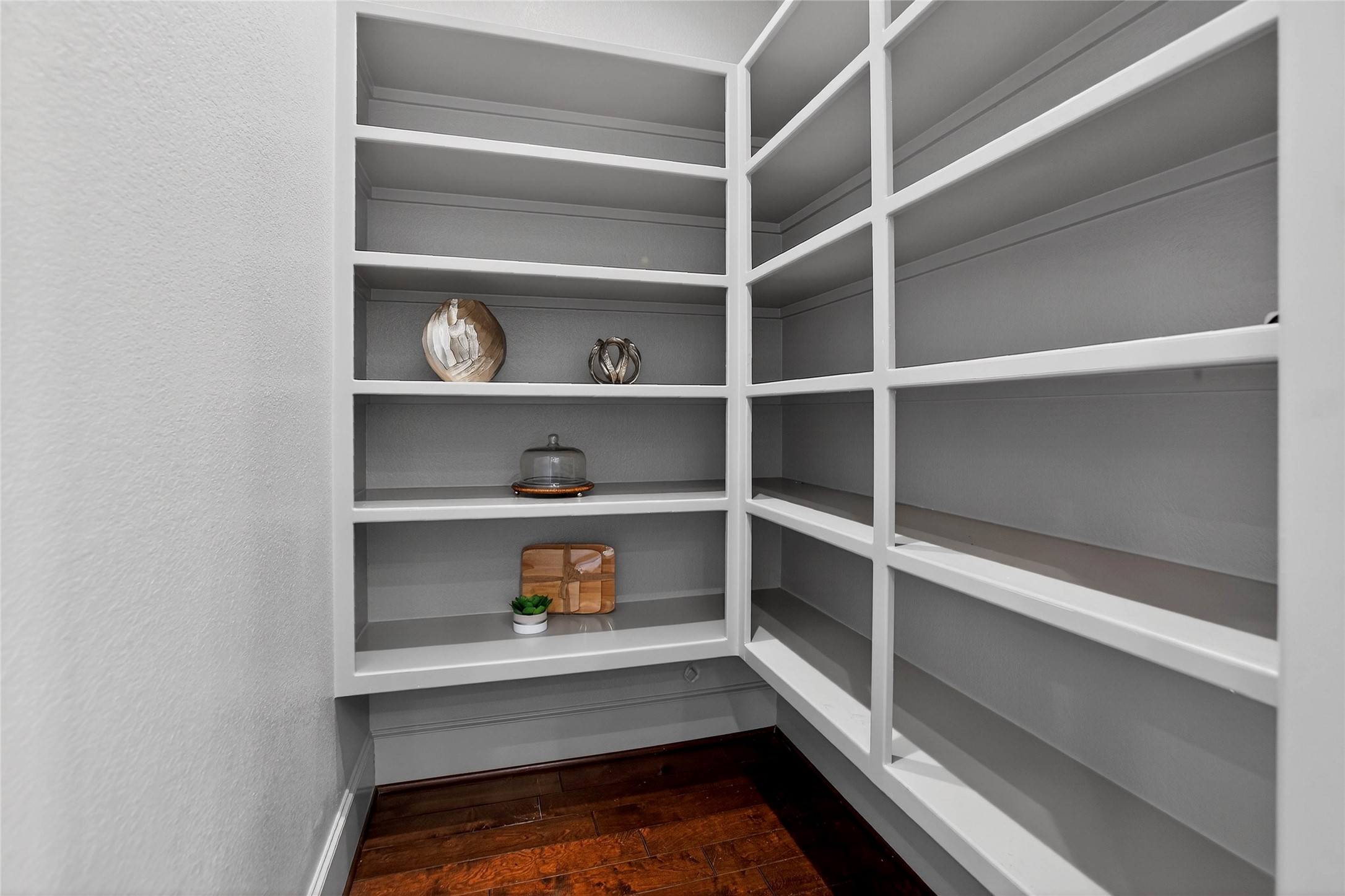 12349 Tramonto Conroe, TX 77304 - Photo 17 of 50 A spacious, well-lit pantry with white shelves perfect for storage, featuring decorative items for a touch of elegance.