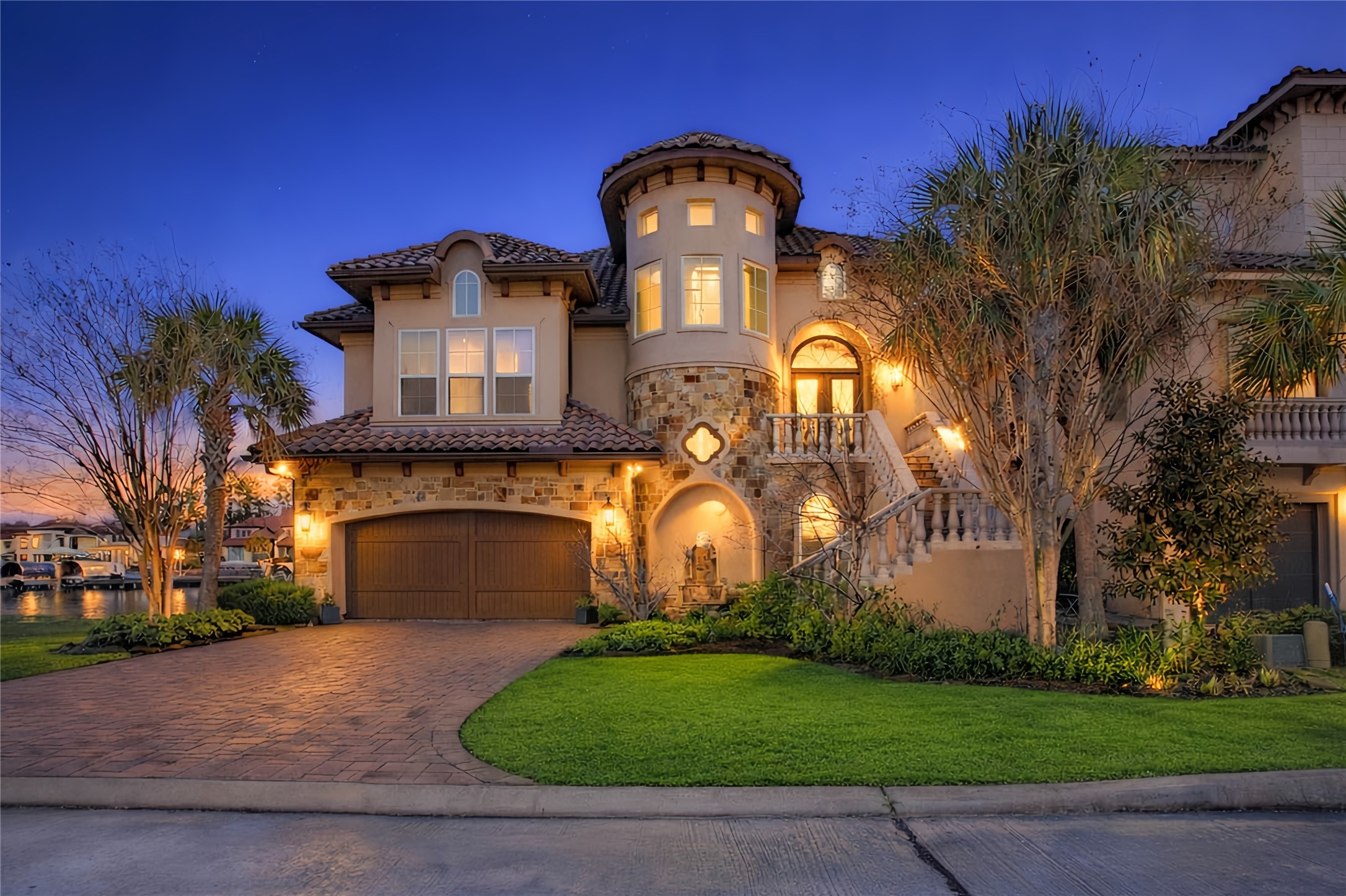 12349 Tramonto Conroe, TX 77304 - Photo 2 of 50 This stunning home features a Mediterranean-style design with elegant stonework, a turret, and warm exterior lighting. The manicured lawn and spacious driveway enhance its curb appeal, while the waterfront location offers scenic views.