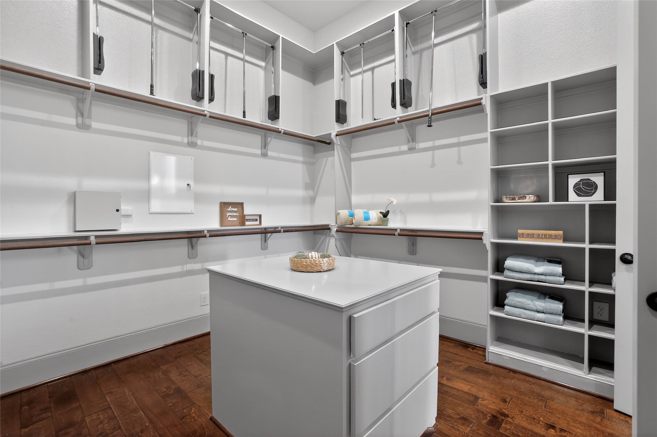 12349 Tramonto Conroe, TX 77304 - Photo 25 of 50 This spacious walk-in closet features hardwood floors, ample hanging space with adjustable racks, built-in shelving for organization, and a central island with drawers for additional storage.