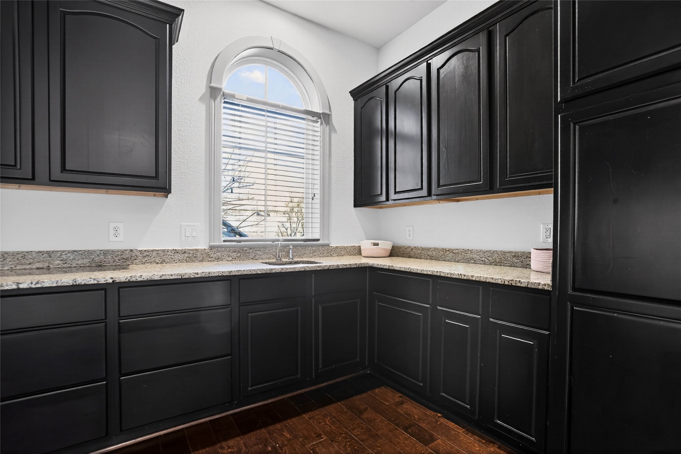 12349 Tramonto Conroe, TX 77304 - Photo 37 of 50 Laundry room on the first floor with elegant dark cabinetry, granite countertops, and a bright window that lets in natural light, creating a warm and inviting atmosphere. Ideal for a modern home.
