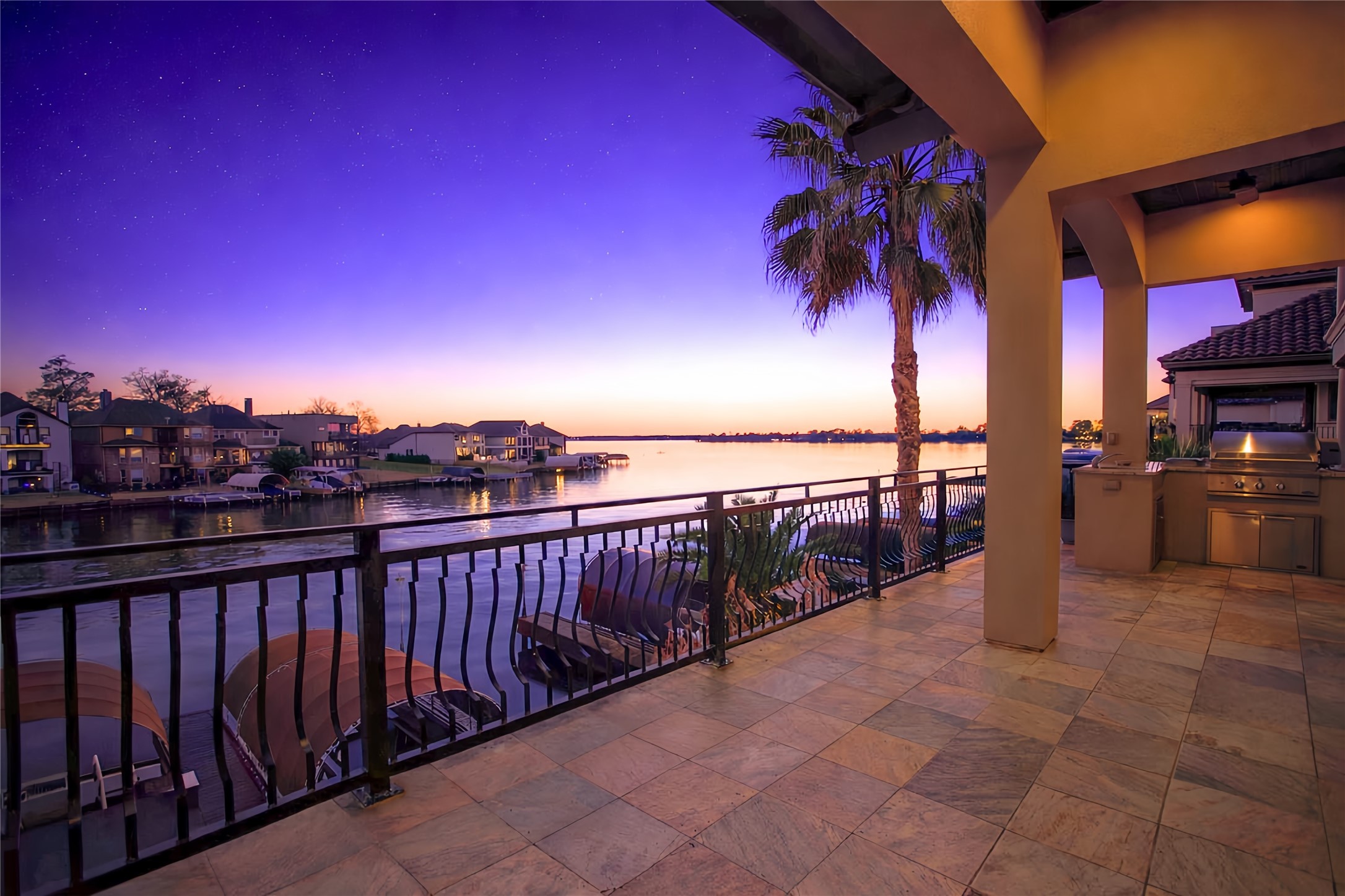 12349 Tramonto Conroe, TX 77304 - Photo 6 of 50 A spacious patio with elegant tile flooring and a built-in outdoor kitchen, overlooking a serene waterfront view at sunset. Perfect for entertaining or relaxing, the scene features a beautiful blend of architecture and natural beauty.