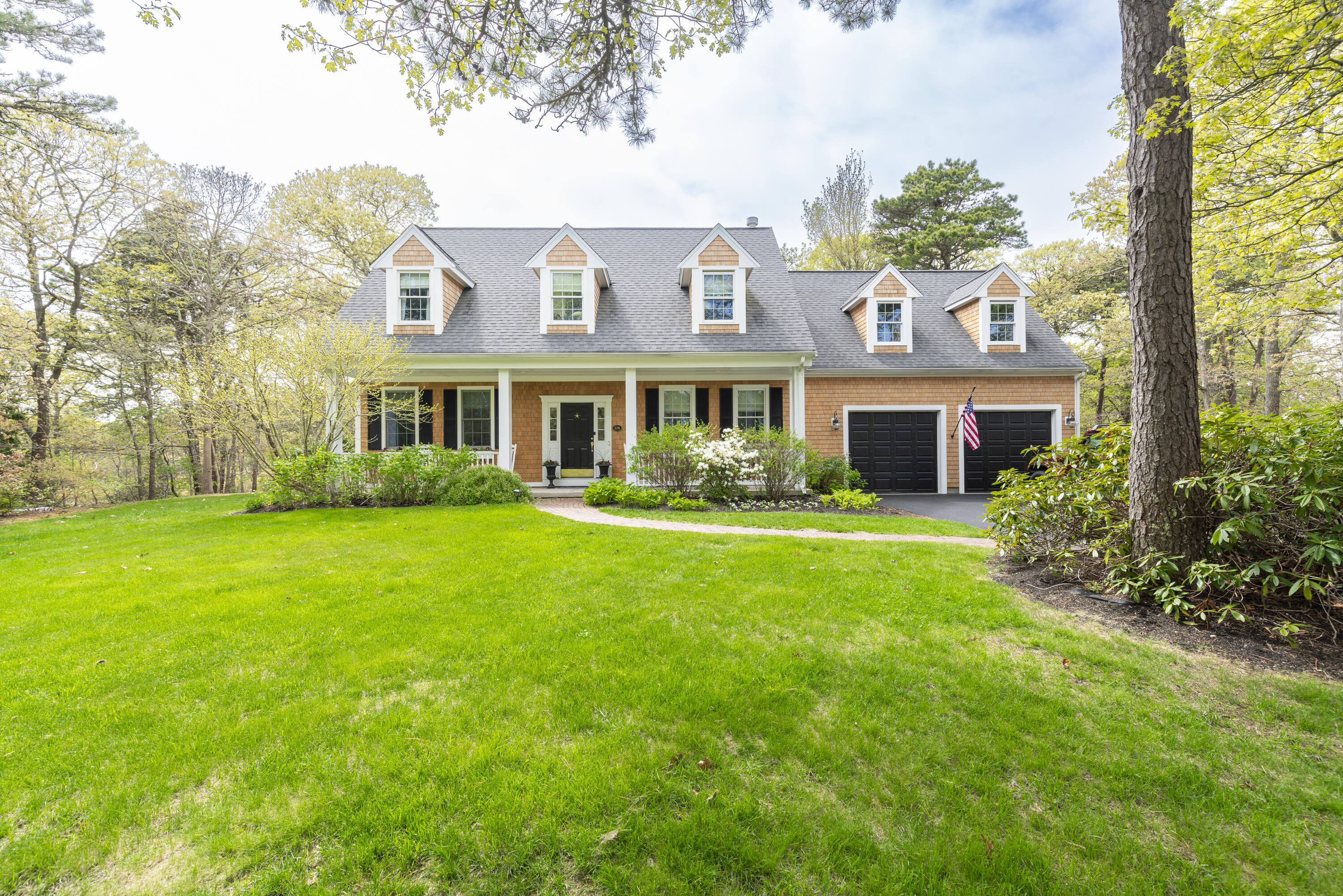a front view of a house with garden and trees