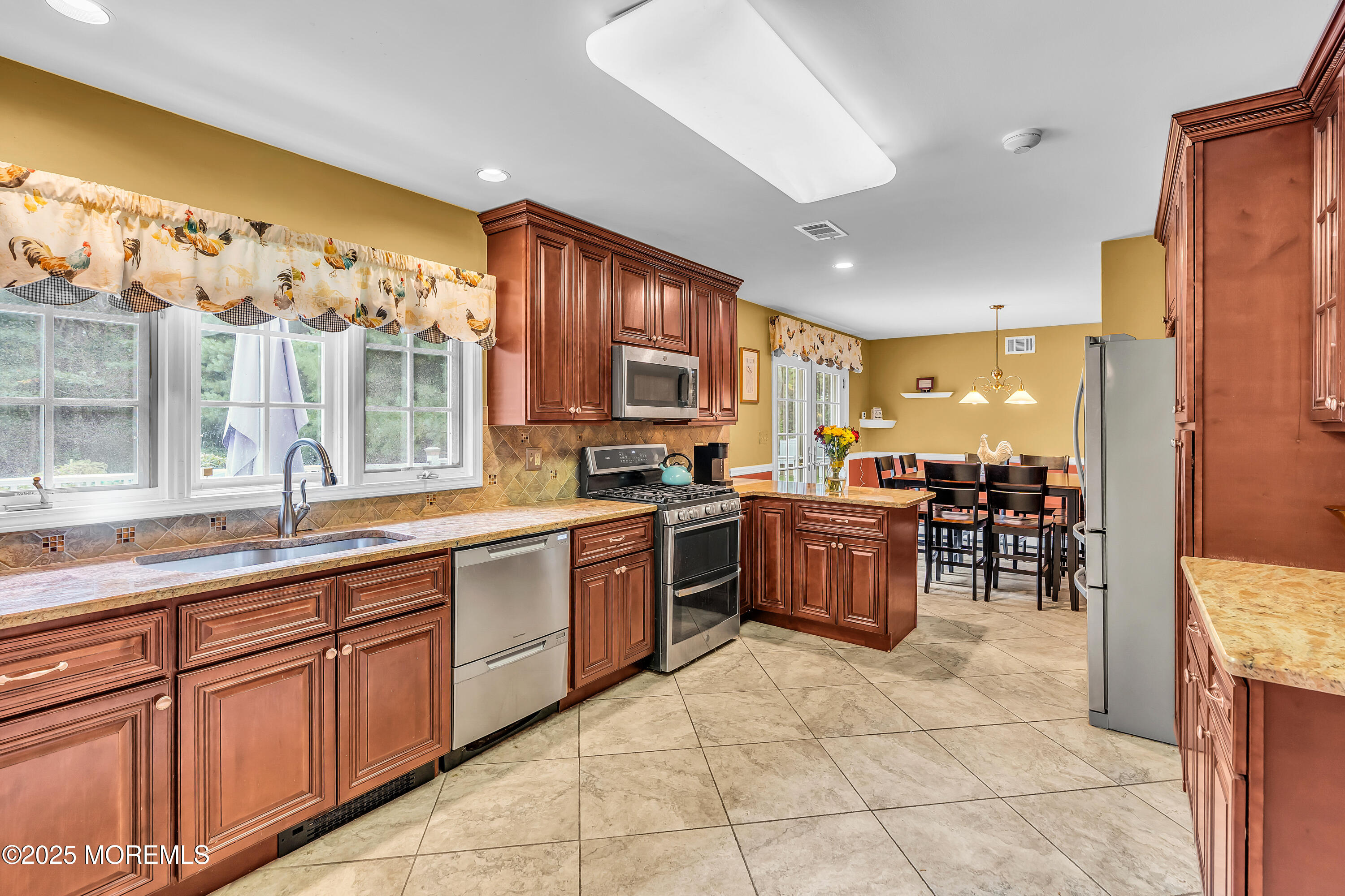 627 Reed Road Jackson, NJ 08527 - Photo 11 of 44 a kitchen with stainless steel appliances granite countertop wooden cabinets a stove a sink and a large window