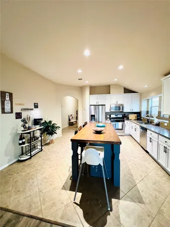 a living room with stainless steel appliances kitchen island granite countertop a sink and cabinets