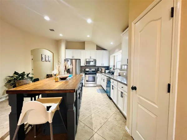 a kitchen with stainless steel appliances granite countertop a table chairs sink and cabinets