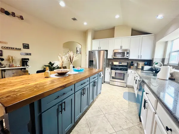 a kitchen with kitchen island granite countertop a sink counter top space appliances and cabinets
