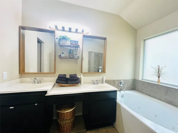 a bathroom with a bathtub double vanity sink and a mirror