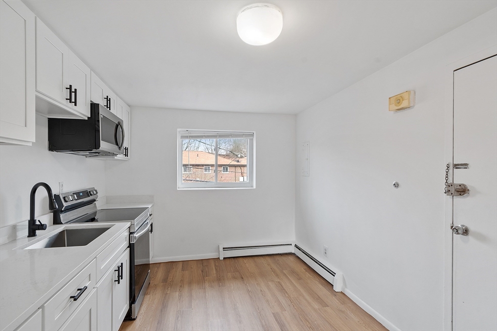 26 Bryon Road, Unit 3 Boston, MA 02467 - Photo 5 of 30 a kitchen with a sink cabinets and a flat screen tv
