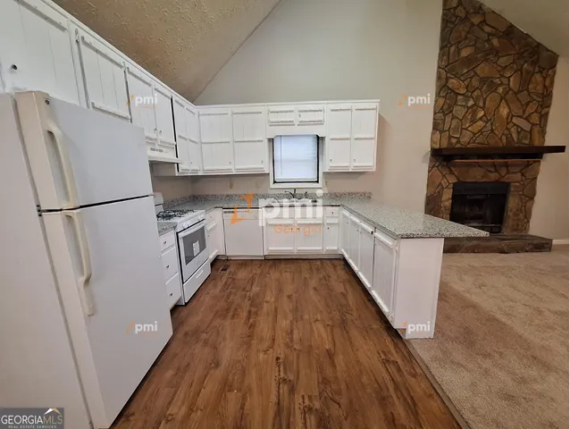 a kitchen with a refrigerator a stove top oven and wooden floor
