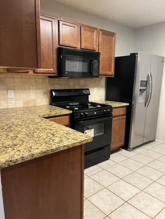 a kitchen with granite countertop a refrigerator stove and microwave