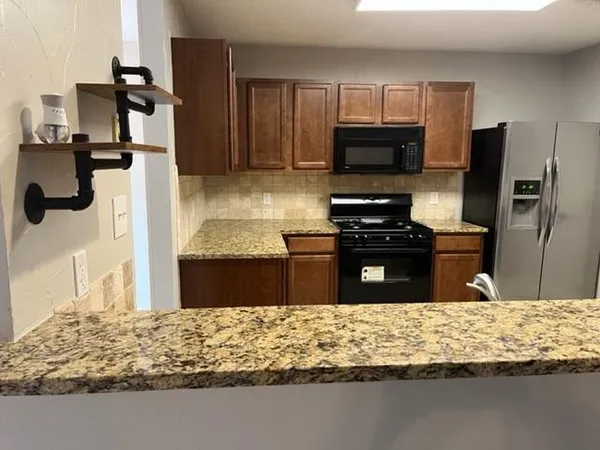 a kitchen with kitchen island granite countertop a refrigerator oven a sink and dishwasher