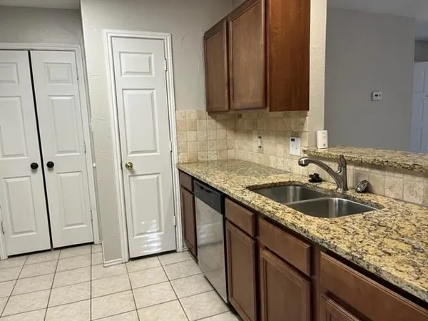 a kitchen with granite countertop a sink and a wooden cabinets