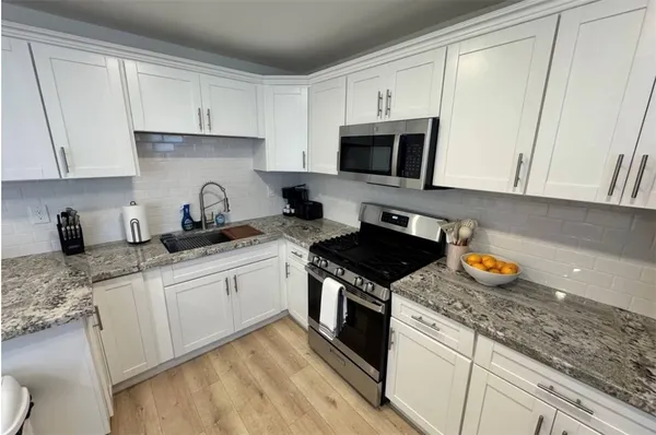 a kitchen with stainless steel appliances granite countertop a sink stove and white cabinets