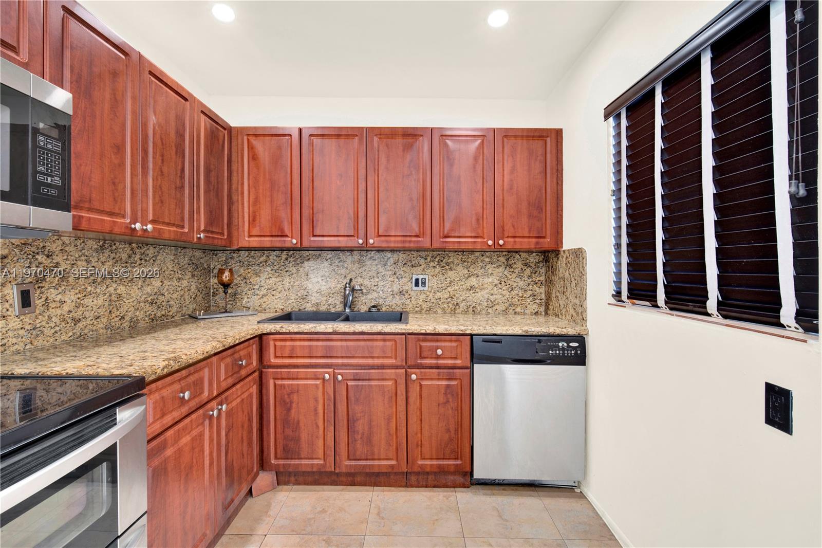 7747 Southwest 86th Street, Unit D403 Miami, FL 33143 - Photo 9 of 25 a kitchen with stainless steel appliances granite countertop a stove and a sink