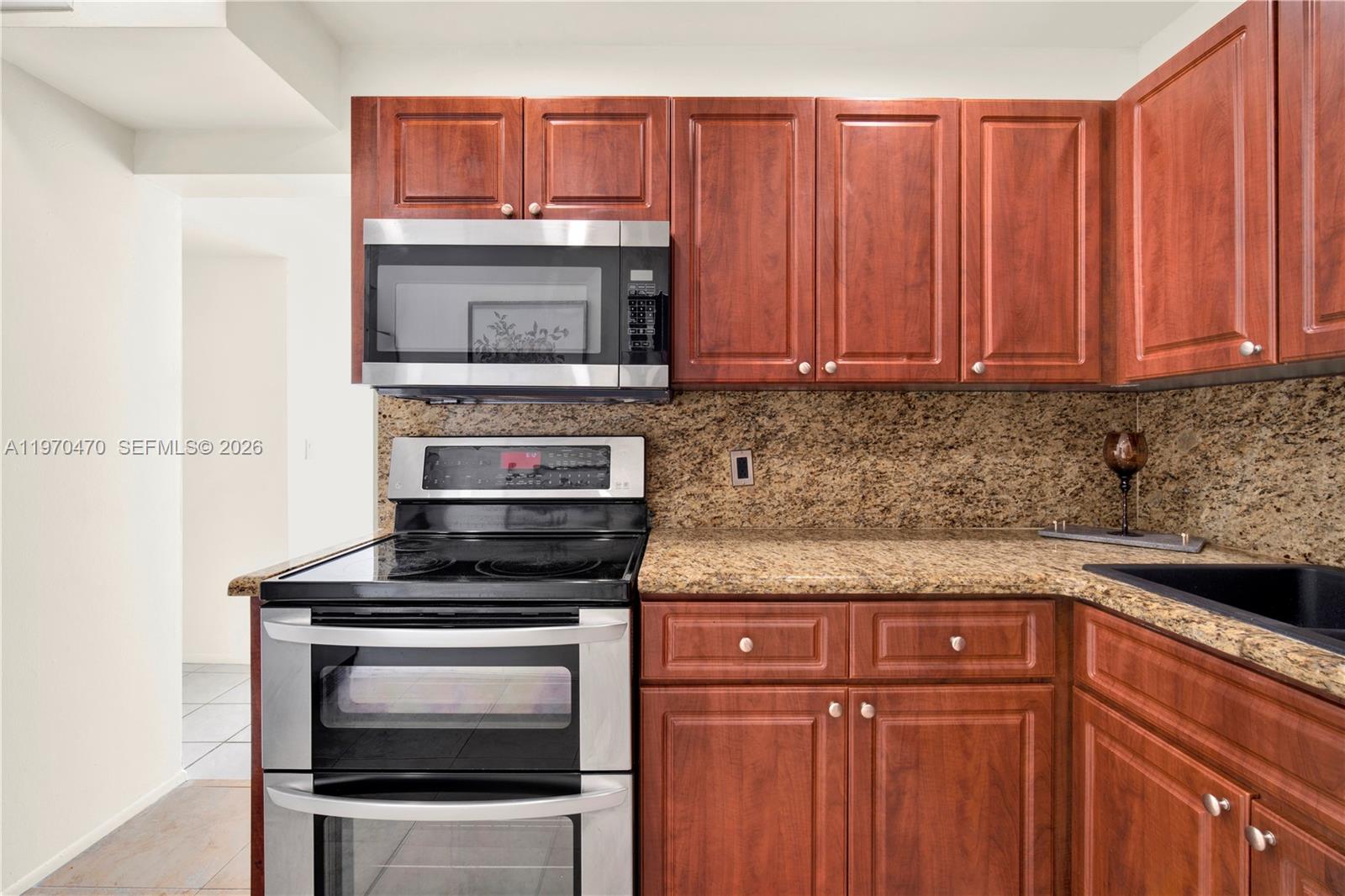 7747 Southwest 86th Street, Unit D403 Miami, FL 33143 - Photo 10 of 25 a kitchen with granite countertop a stove and a microwave