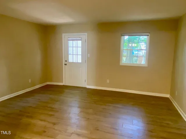 a view of an empty room with wooden floor and a window