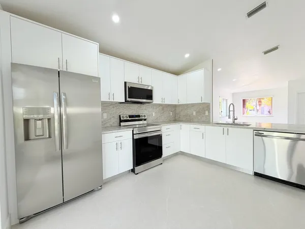 a kitchen with white cabinets and refrigerator