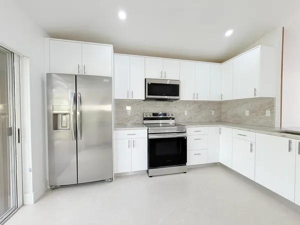 a kitchen with stainless steel appliances granite countertop a refrigerator a stove a sink and a microwave