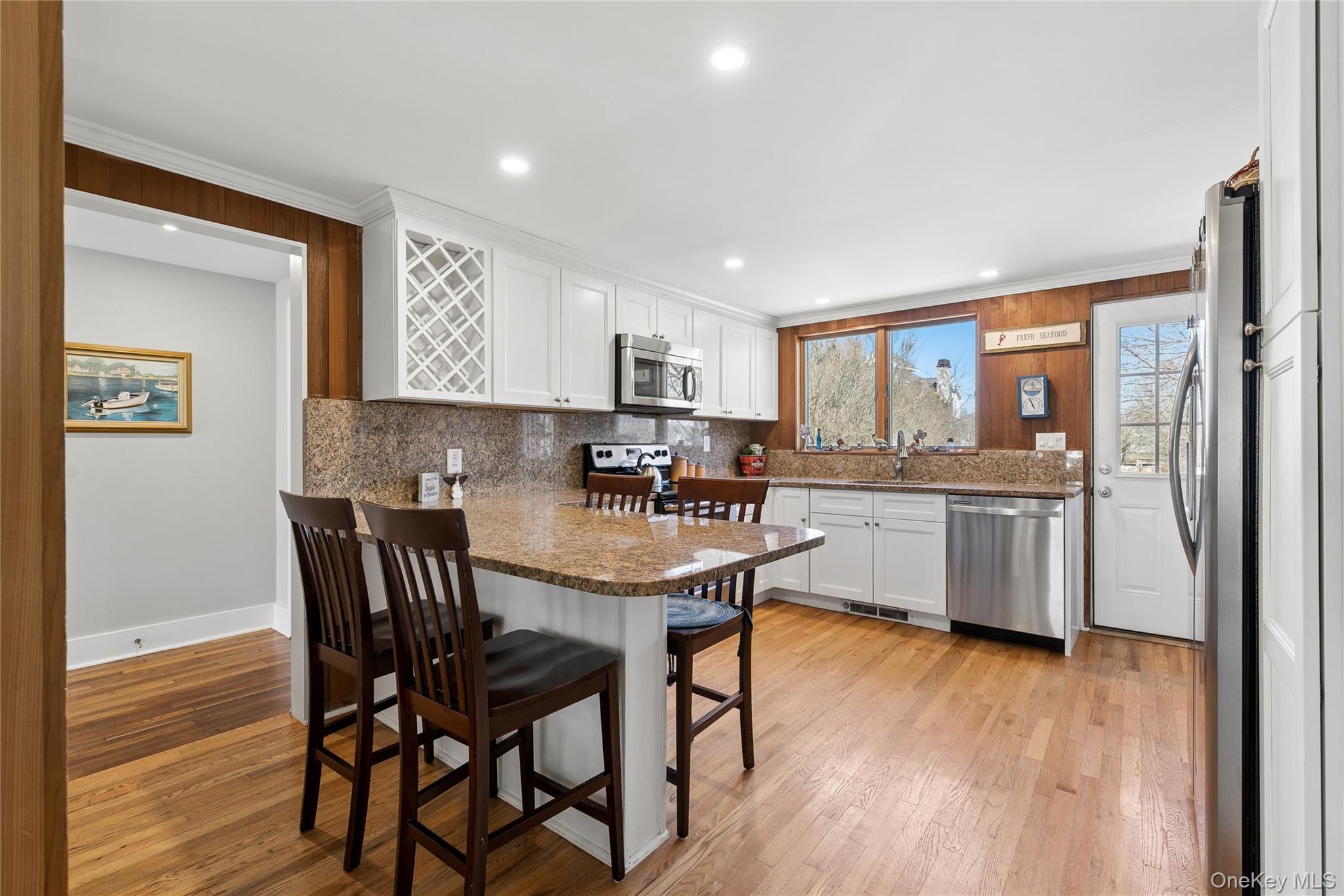 20 Mitchell Road Westhampton Beach, NY 11978 - Photo 7 of 34 a kitchen with stainless steel appliances granite countertop a stove a refrigerator a sink a dining table and chairs with wooden floor