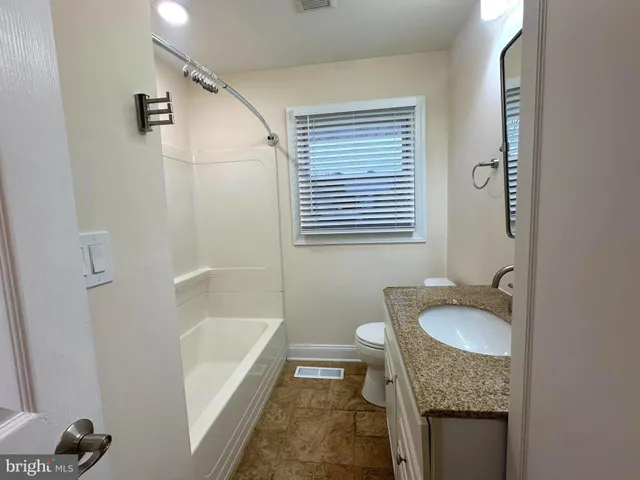 a bathroom with a granite countertop sink toilet and shower