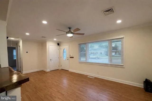 a view of an empty room with wooden floor and a window