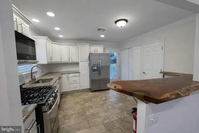 a kitchen that has a sink a center island stainless steel appliances and cabinets