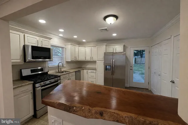 a kitchen with stainless steel appliances granite countertop a refrigerator a stove and a sink