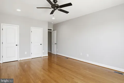 an empty room with windows and ceiling fan