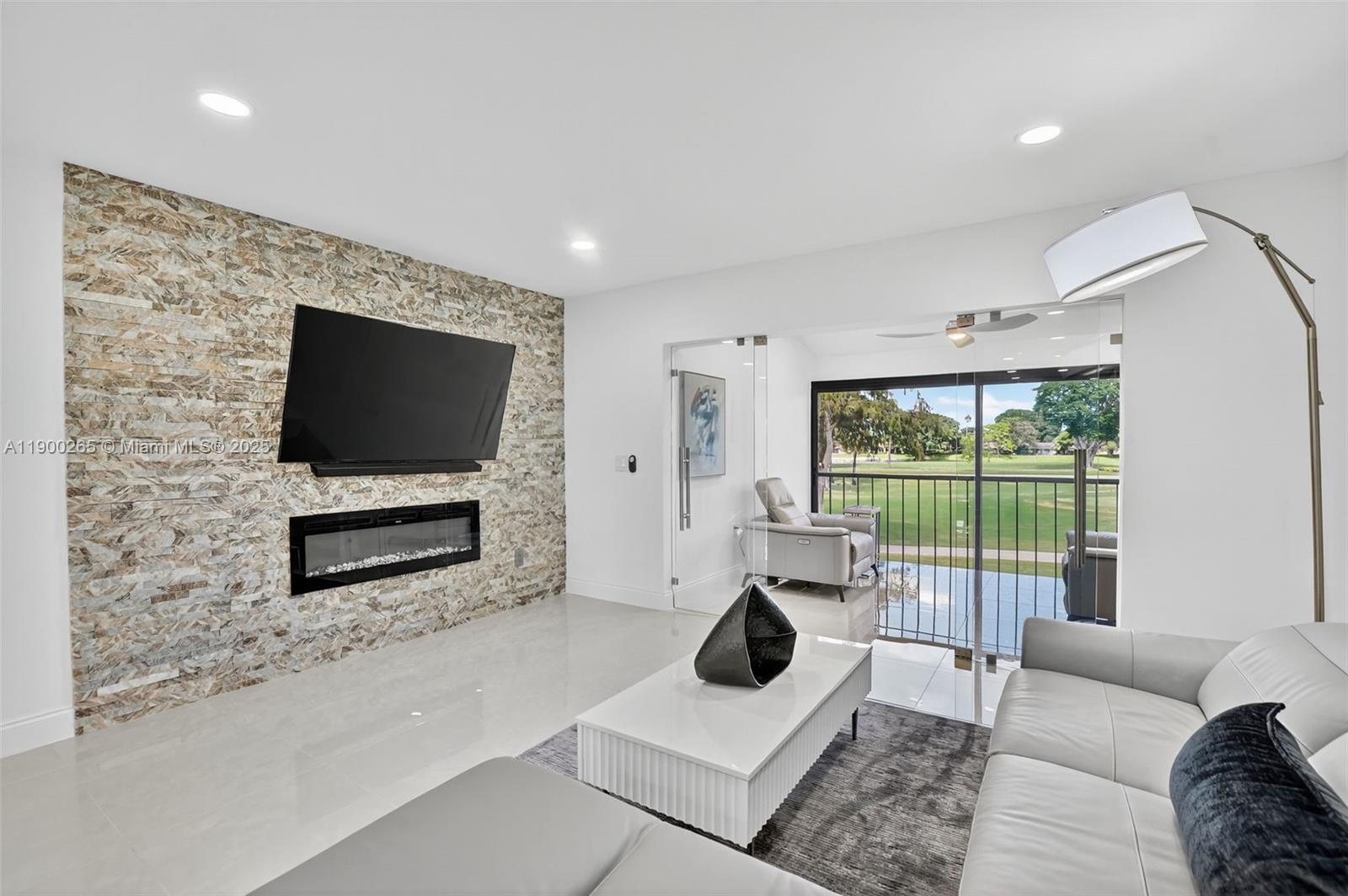 21860 Arriba Real, Unit 4D Boca Raton, FL 33433 - Photo 12 of 55 a living room with furniture a flat screen tv and a floor to ceiling window