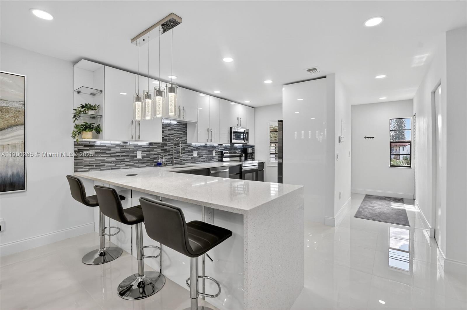 21860 Arriba Real, Unit 4D Boca Raton, FL 33433 - Photo 6 of 55 a kitchen with stainless steel appliances kitchen island granite countertop a table chairs and a refrigerator