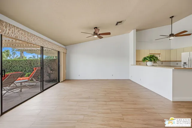 a white kitchen with granite countertop a stove a sink and a refrigerator with wooden floors