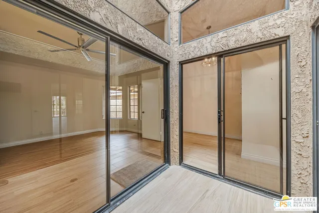 a view of empty room with wooden floor and ceiling fan