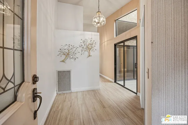 a view of a hallway with wooden floor and a chandelier