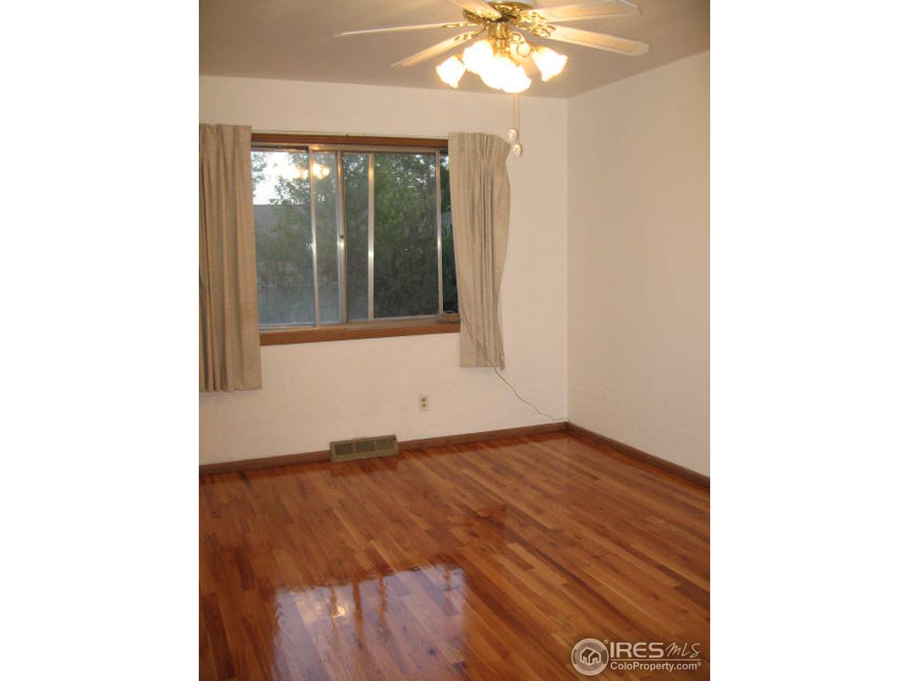 1208 Baker Street Fort Collins, CO 80524 - Photo 12 of 25 a view of an empty room with wooden floor and a window